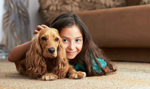 a young girl and her dog lying on the carpet together